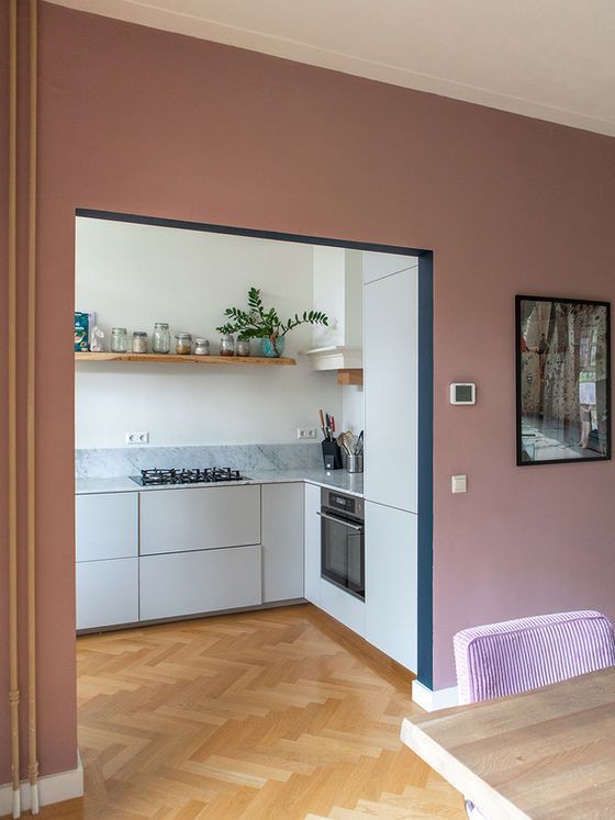Keukeninterieur met mauve muren, witte kasten en houten vloer.
