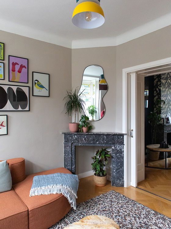 Woonkamerhoek met een open haard, spiegel, kunst en een oranje bank.