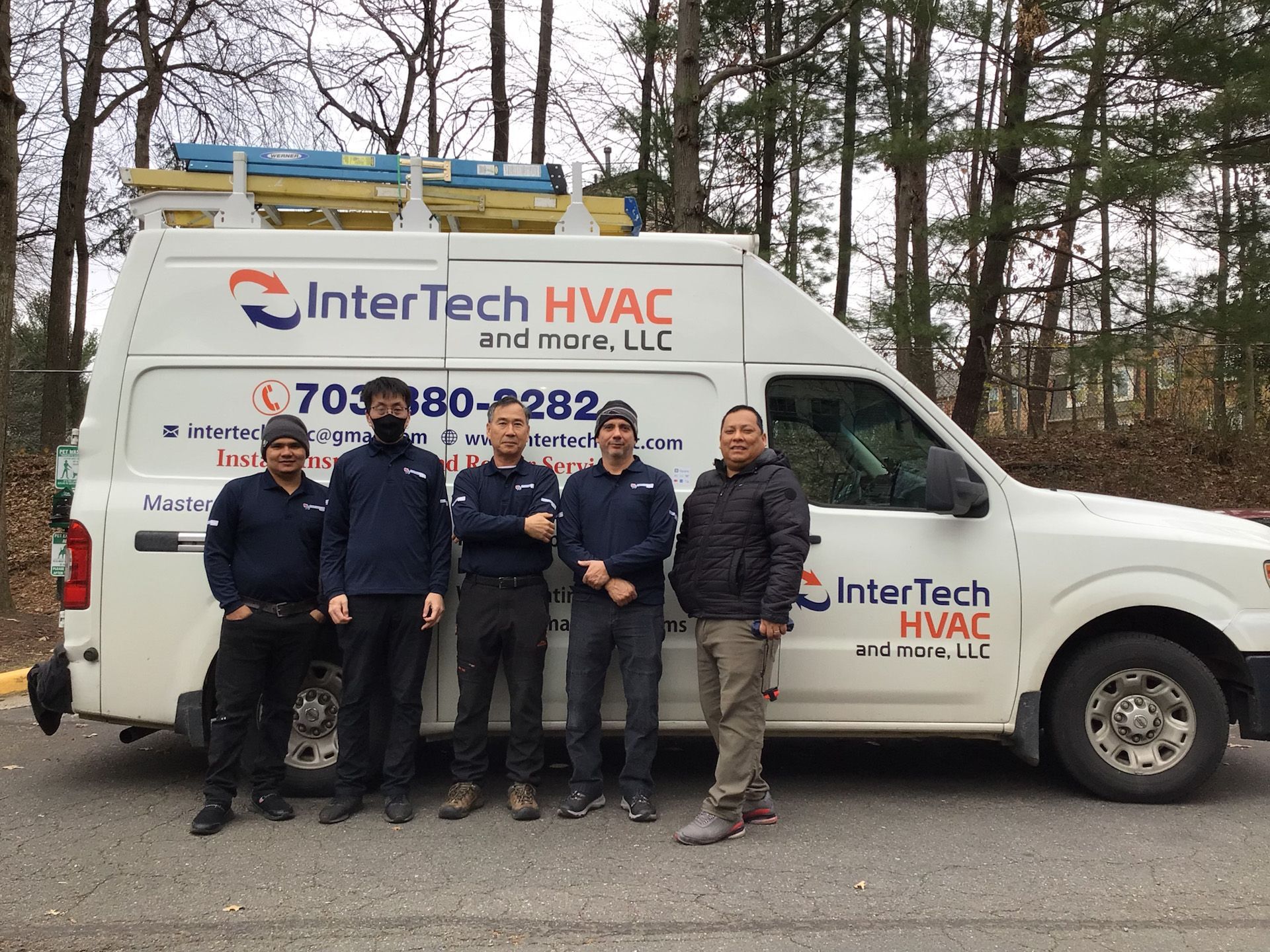 A group of men standing in front of an intertech hvac van