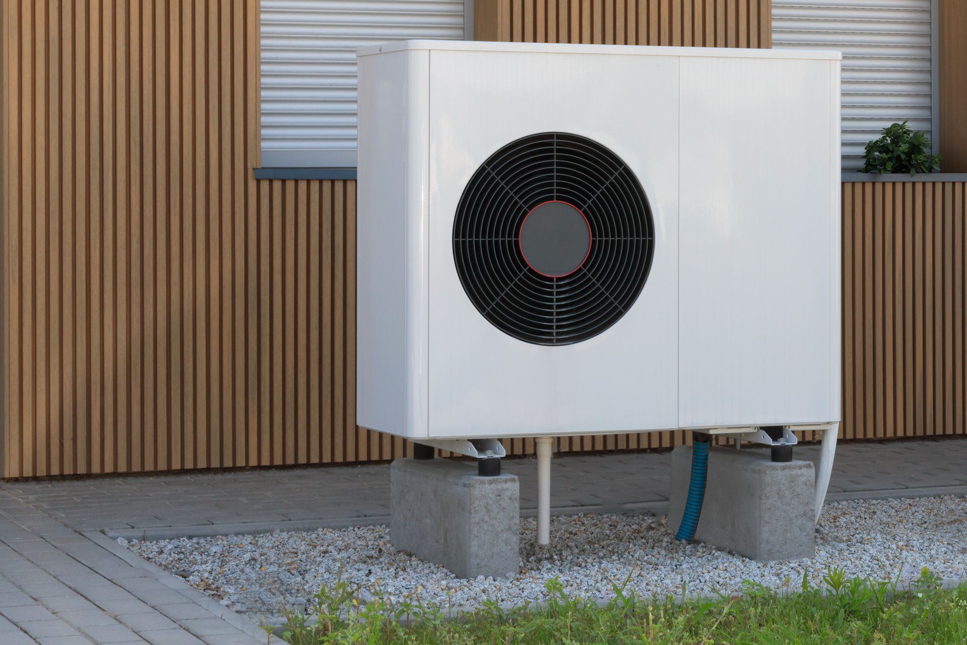 A white air conditioner is sitting in front of a wooden building.