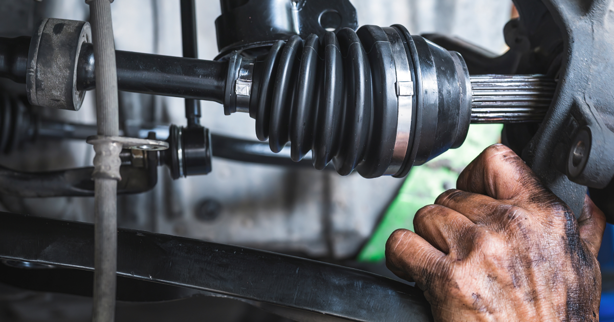 Mechanic’s greasy hands repairing a car CV axle near the wheel assembly | Sunshine Service Automotive Specialists