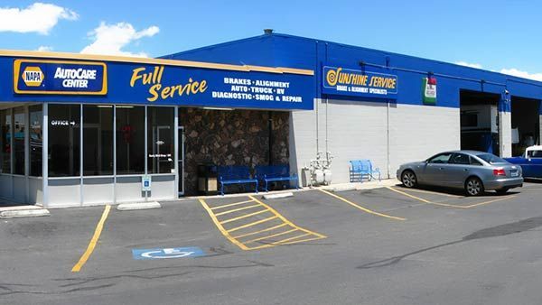 Auto service shop with blue exterior, parked car, and accessible parking space in front | Sunshine Service Automotive Specialists