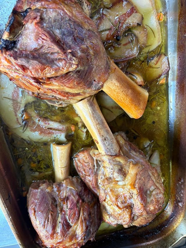Ossa di carne arrostite in una teglia con verdure rosolate e brodo