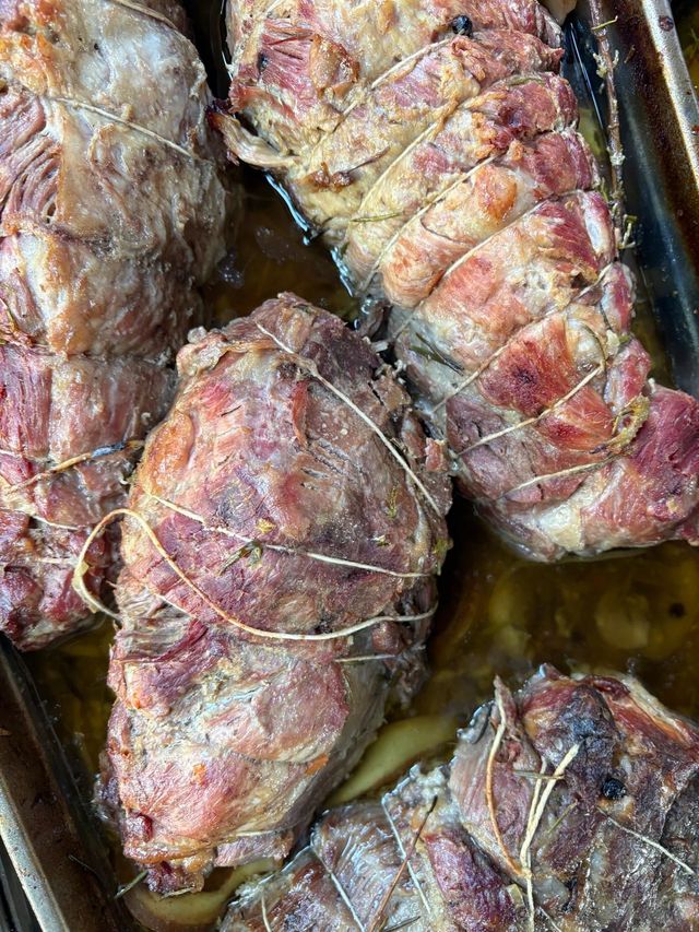 Pezzi di carne arrosto legati e conditi con spezie dorate, primo piano in una padella