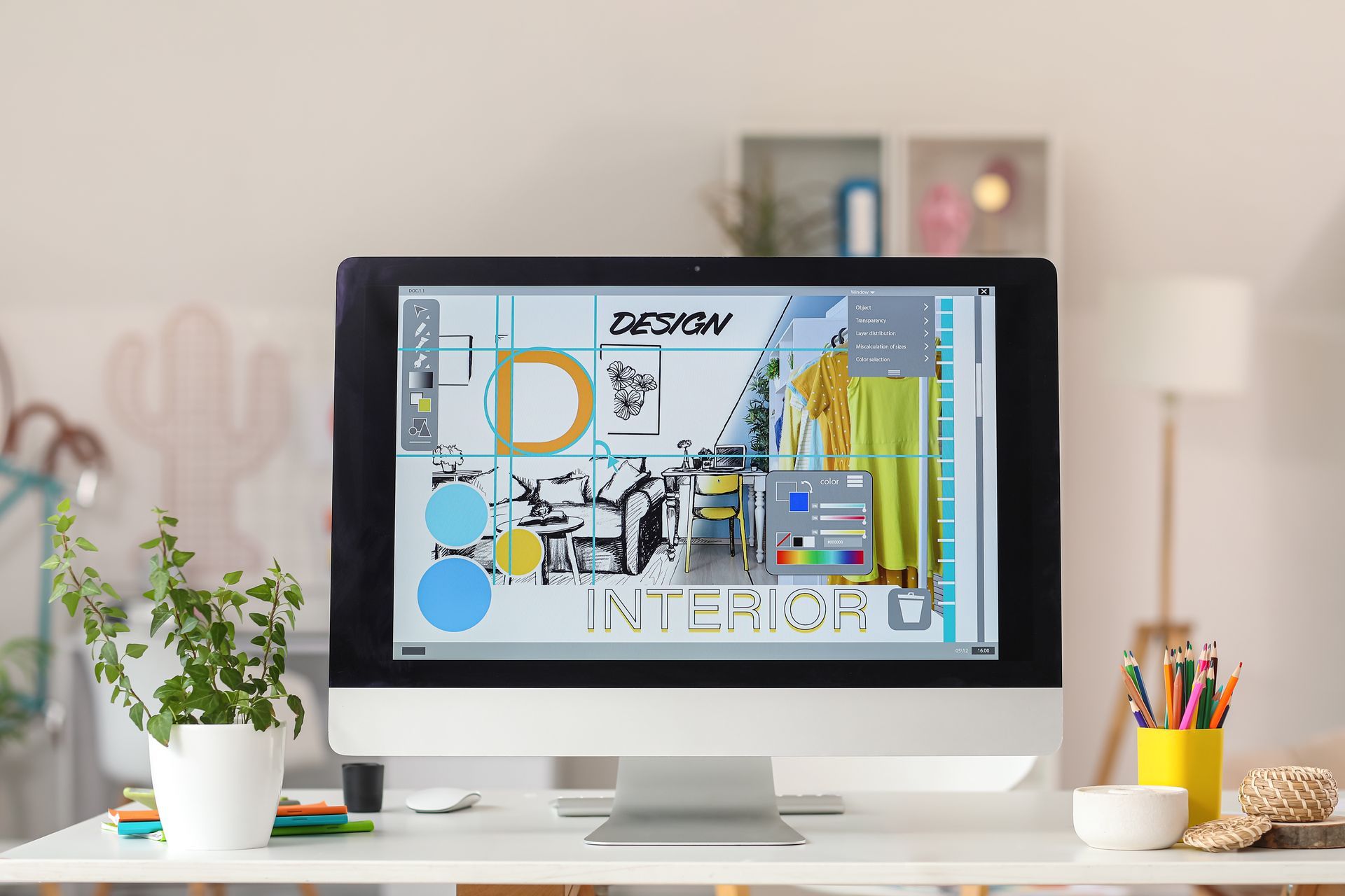 Desktop monitor displaying a colorful design layout on a tidy desk with plants and stationery