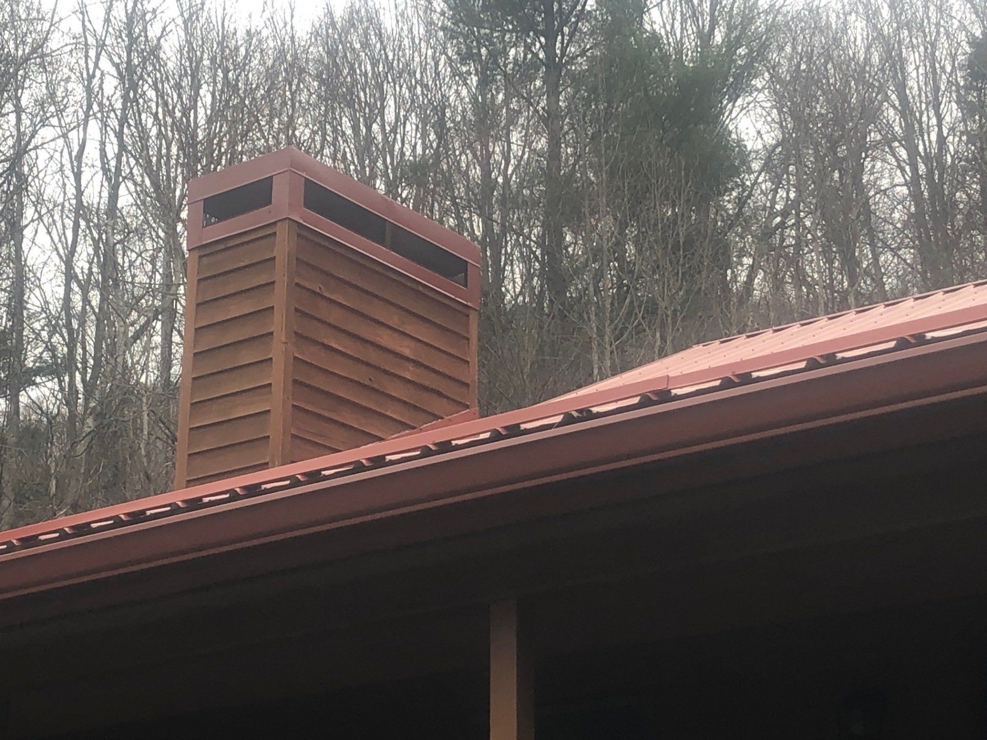 A Chimney On The Roof Of A House With Trees In The Background | Jefferson, NC | Sheets Brothers, Inc.