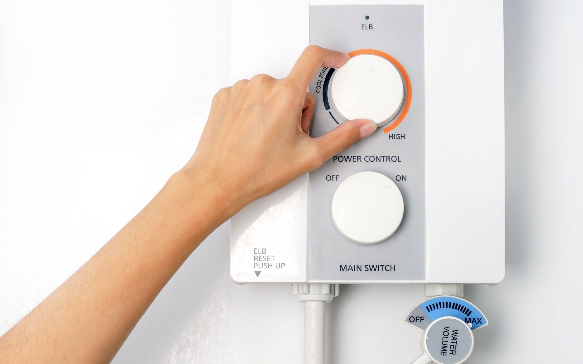 A person's hand turning a dial on a white water heater control panel, adjusting the temperature.