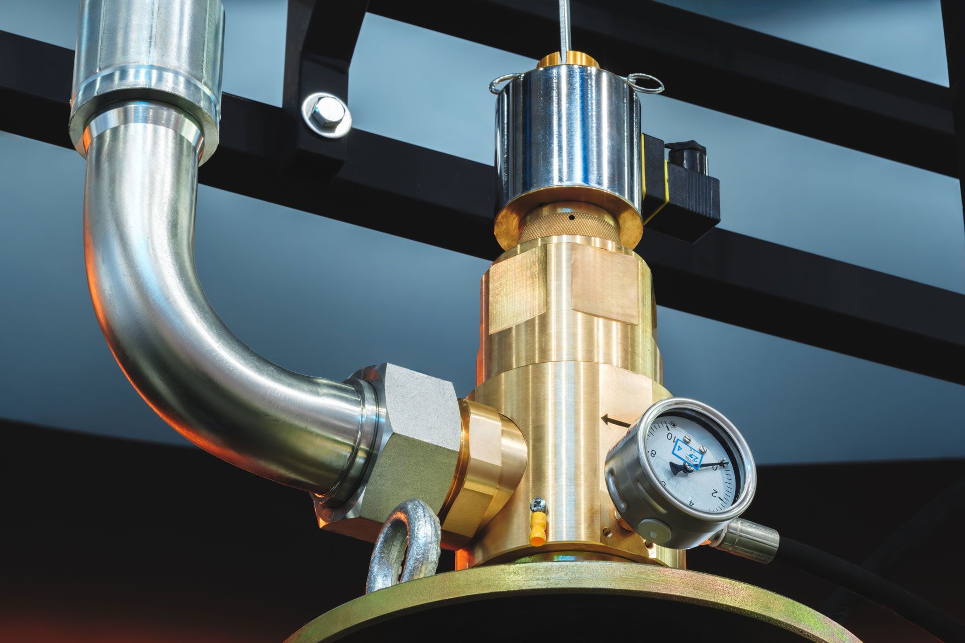 A brass and steel industrial valve with a pressure gauge, pipes, and a top-mounted cylindrical component.