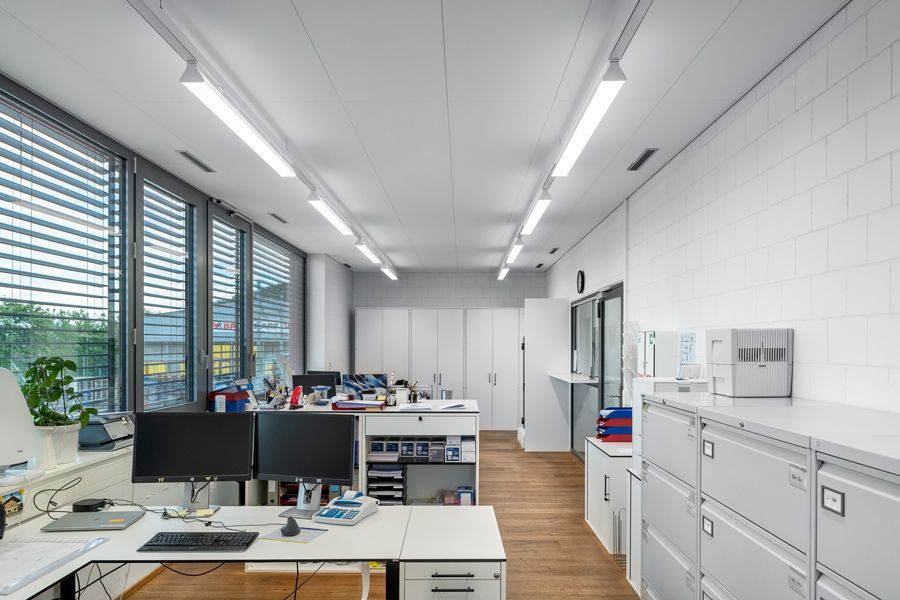 Ein grosses Büro mit vielen Fenstern und einem Schreibtisch mit einem Computer darauf.