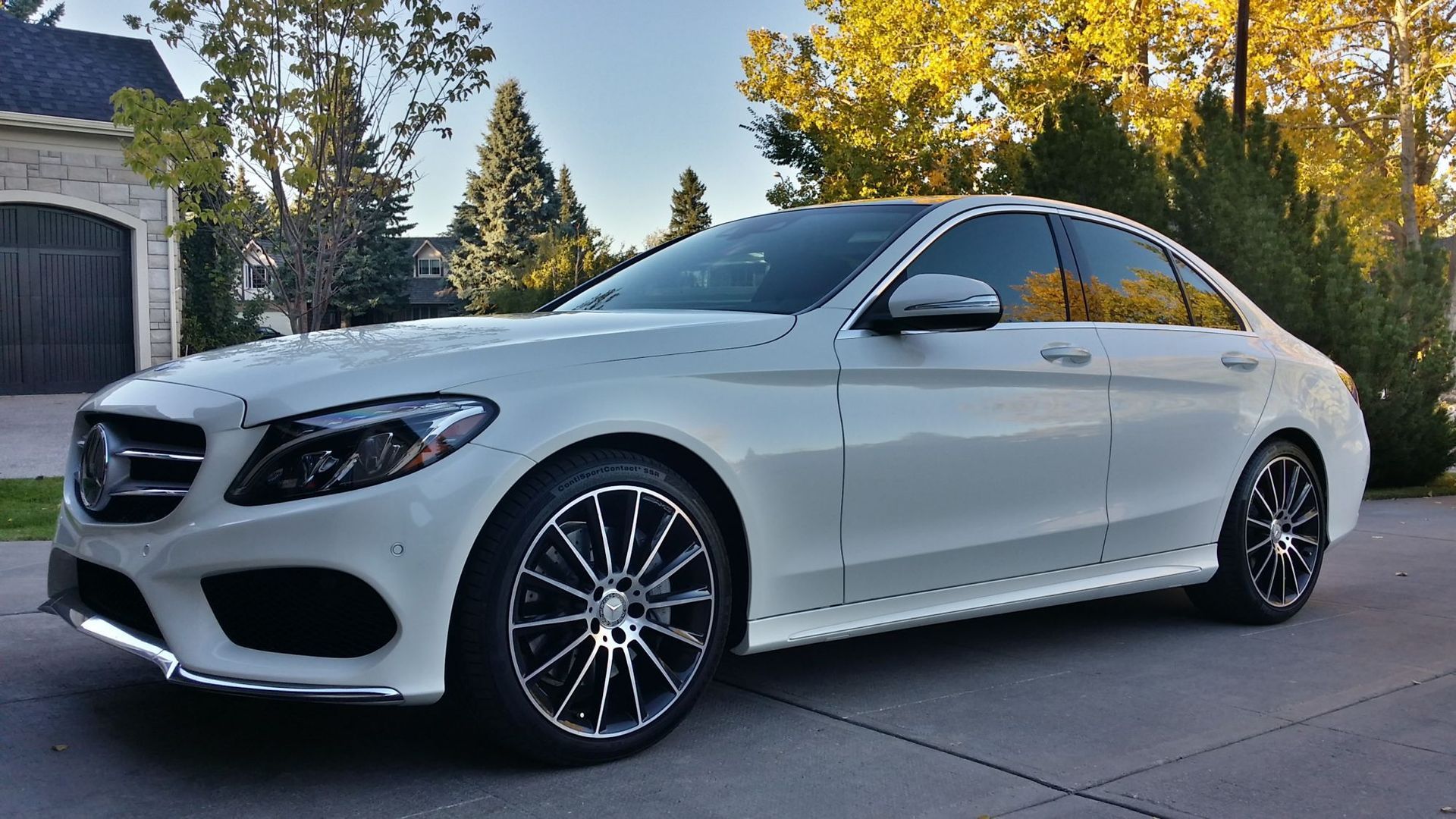 A white mercedes benz c class is parked in a driveway.