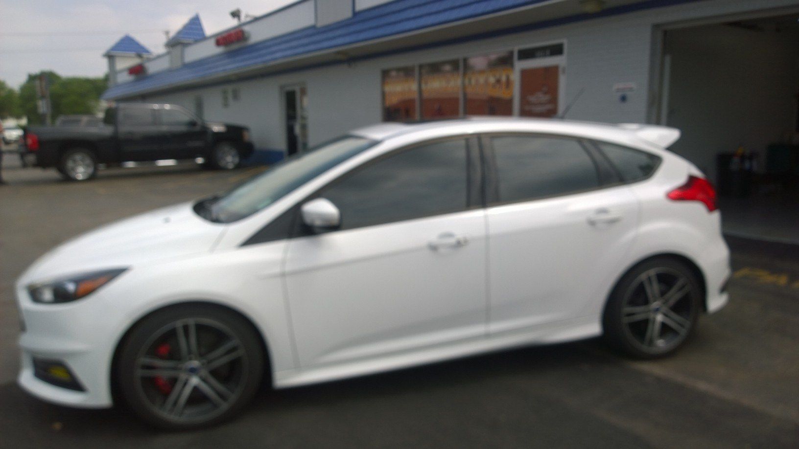 A white car is parked in front of a building