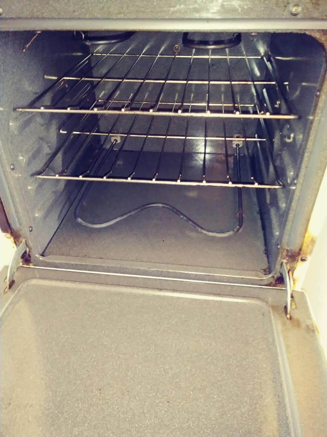 An open, empty oven interior showing two wire racks and a heating element on the floor.