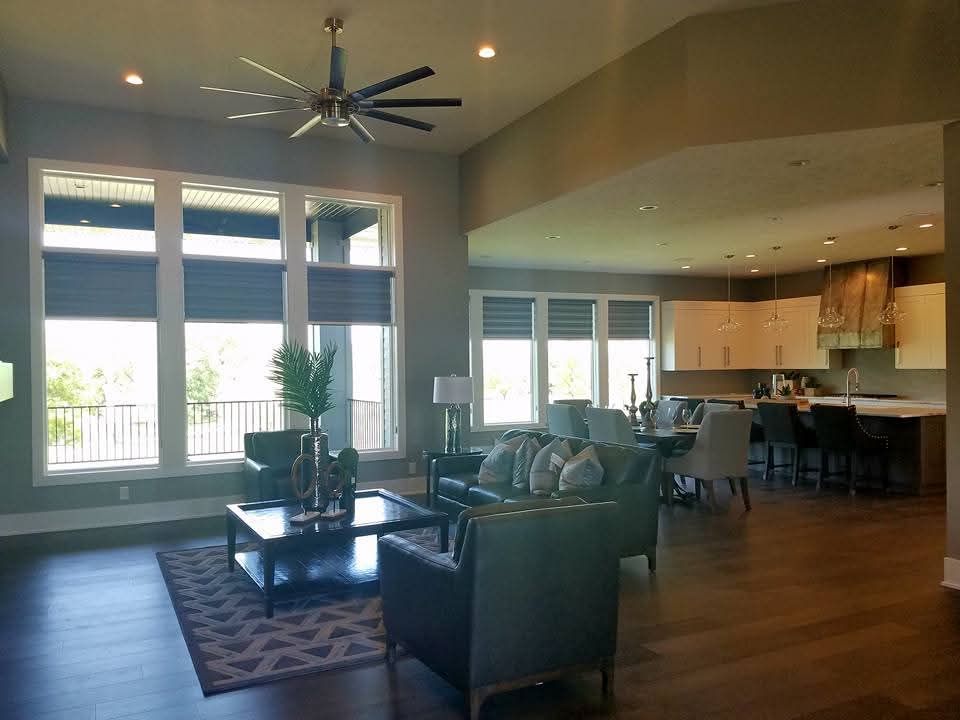 Open-concept living room with gray walls, leather furniture, a patterned rug, and a modern kitchen in the background.