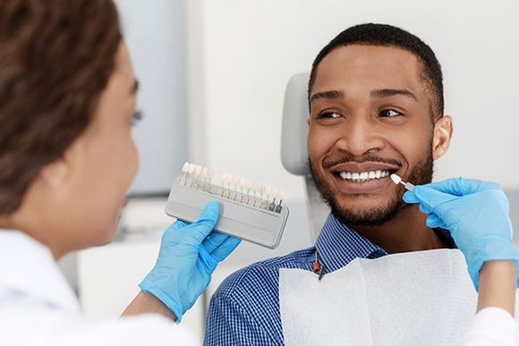 Dentist Choosing Filling Shade for Smiling Patient — Daleville, IN — Daleville Family Dentistry Dentist Choosing Filling Shade for Smiling Patient — Daleville, IN — Daleville Family Dentistry