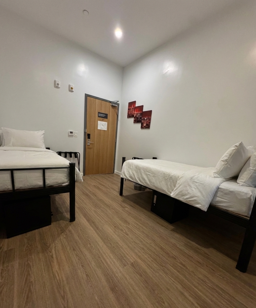 Spacious bedroom with a large bed, seating area, and glass-enclosed shower, all with natural light.