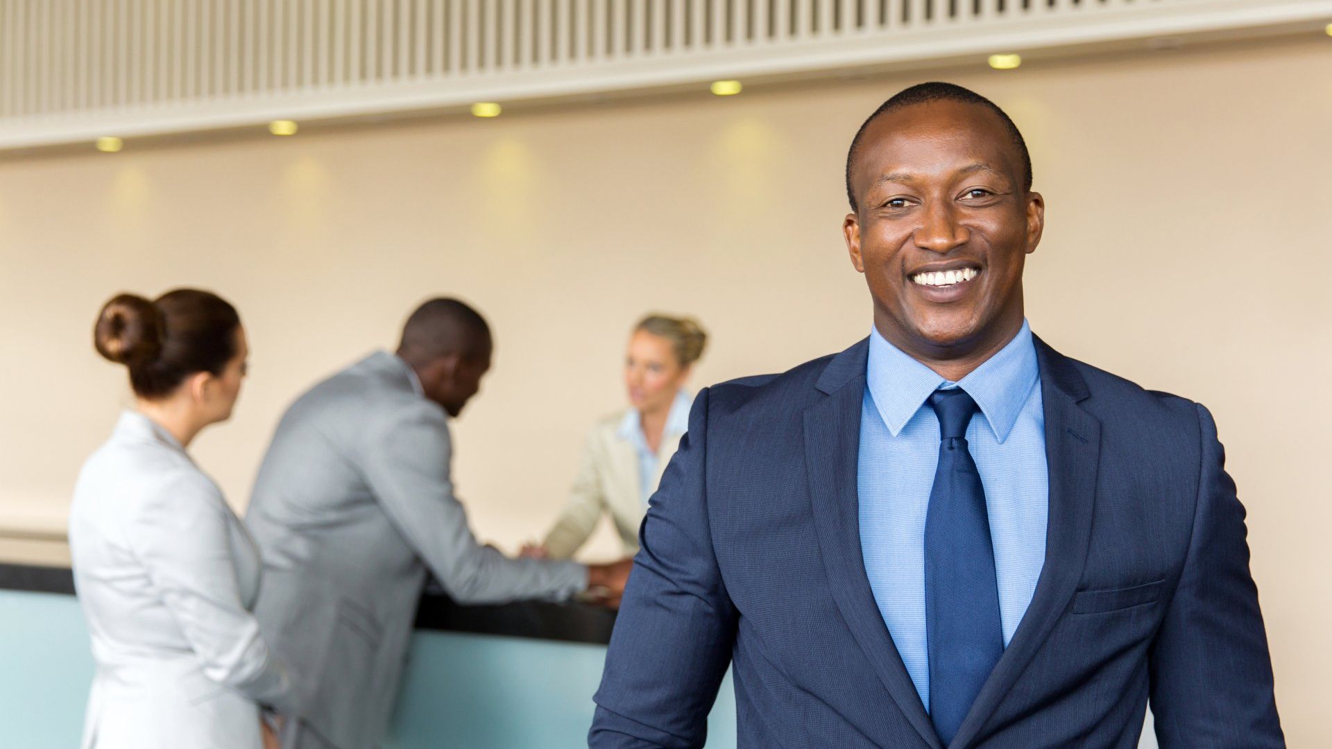 A man in a suit and tie is smiling in a hotel lobby.