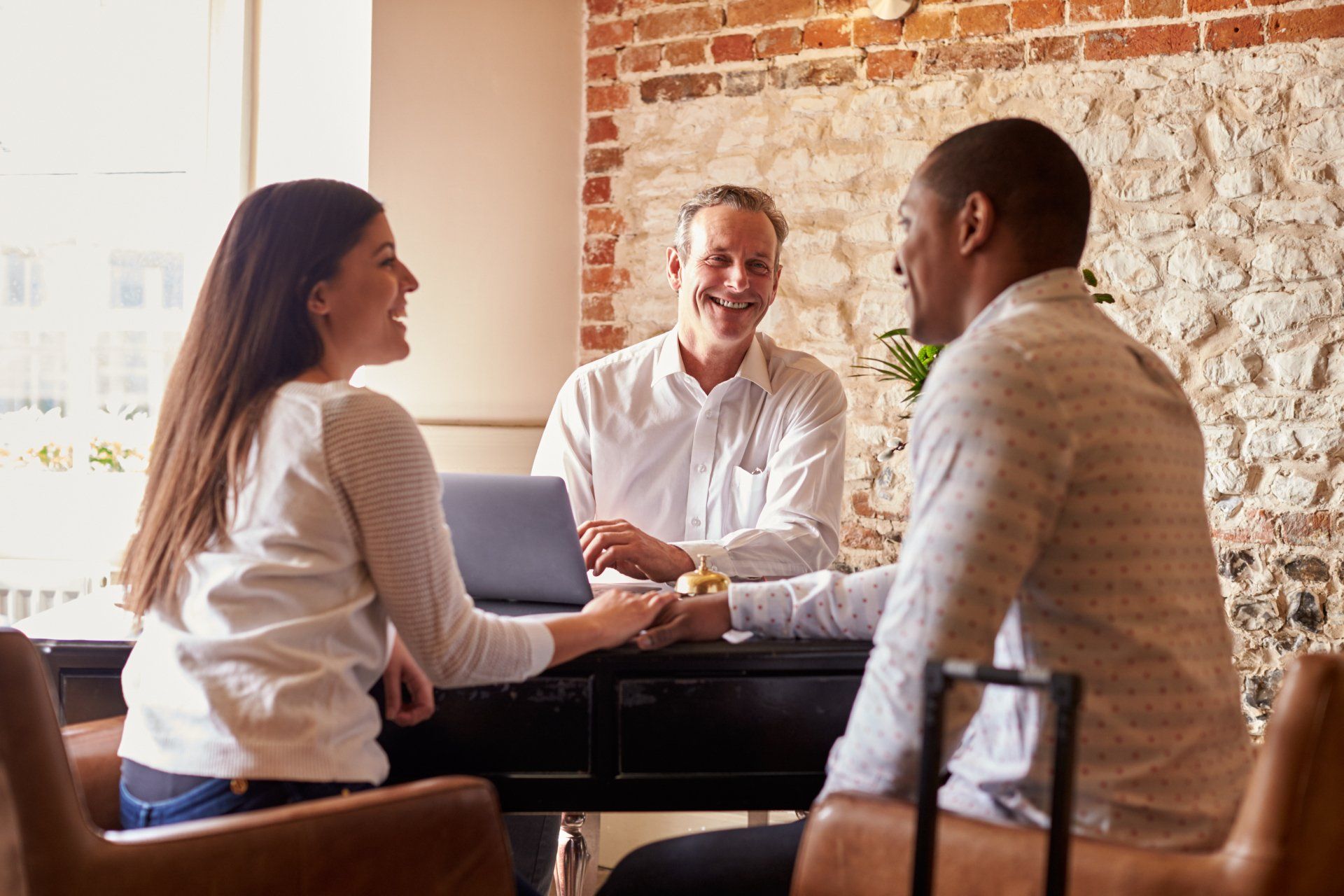 A man and a woman are sitting at a table with a laptop.