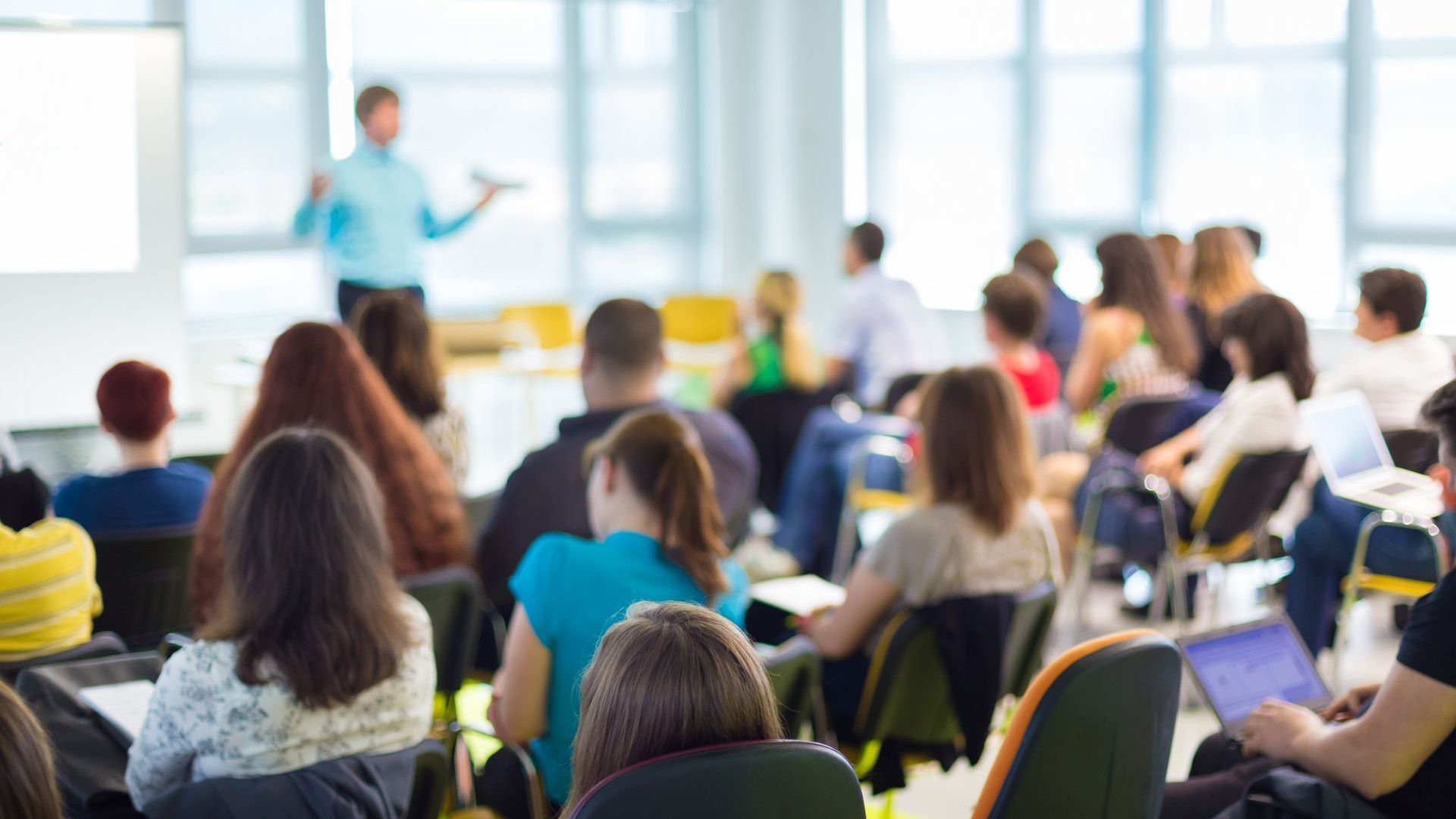 A group of people are sitting in a classroom listening to a lecture.