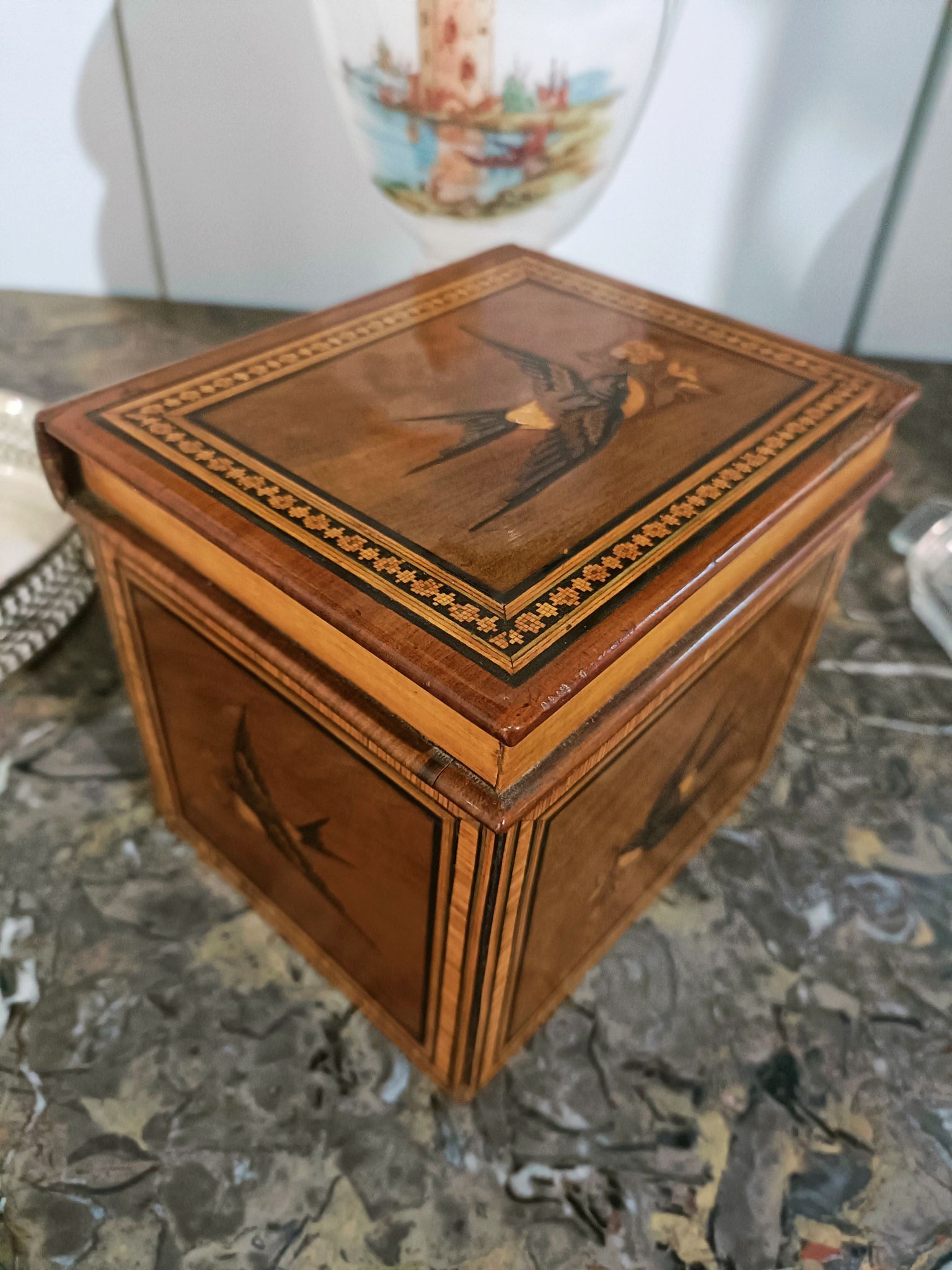 Una scatola di legno con un uccello sopra è appoggiata su un tavolo.