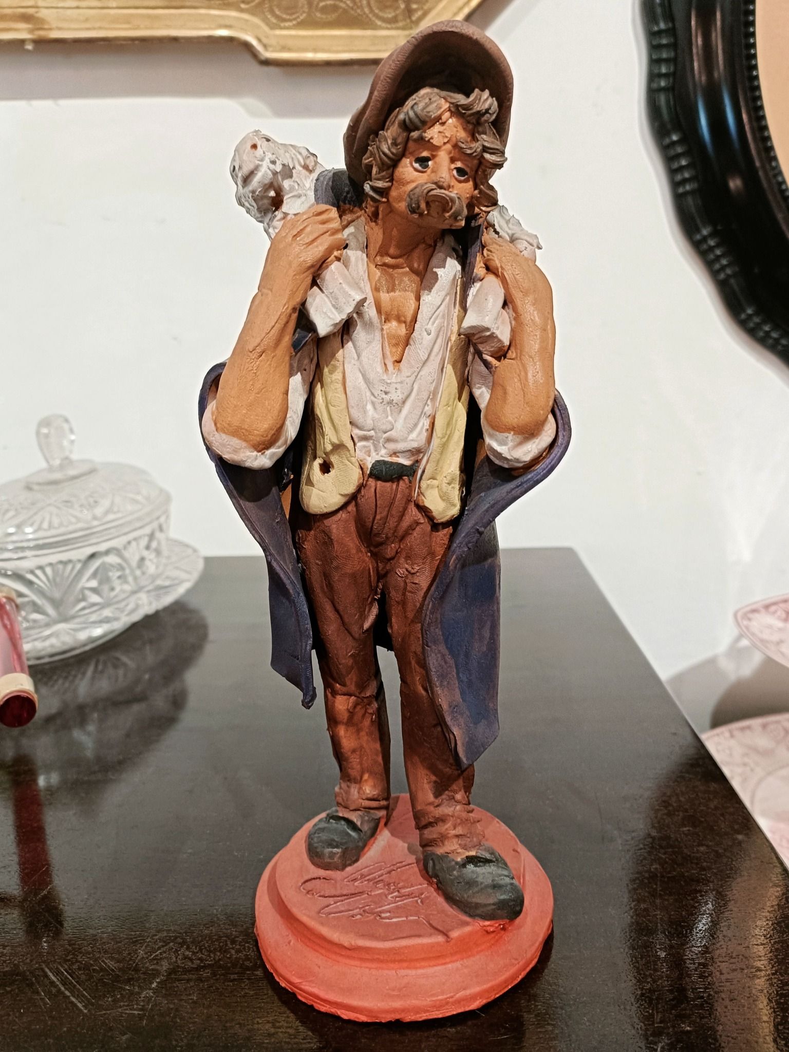 Su un tavolo è seduta la statua di un uomo che porta una pecora sulle spalle.