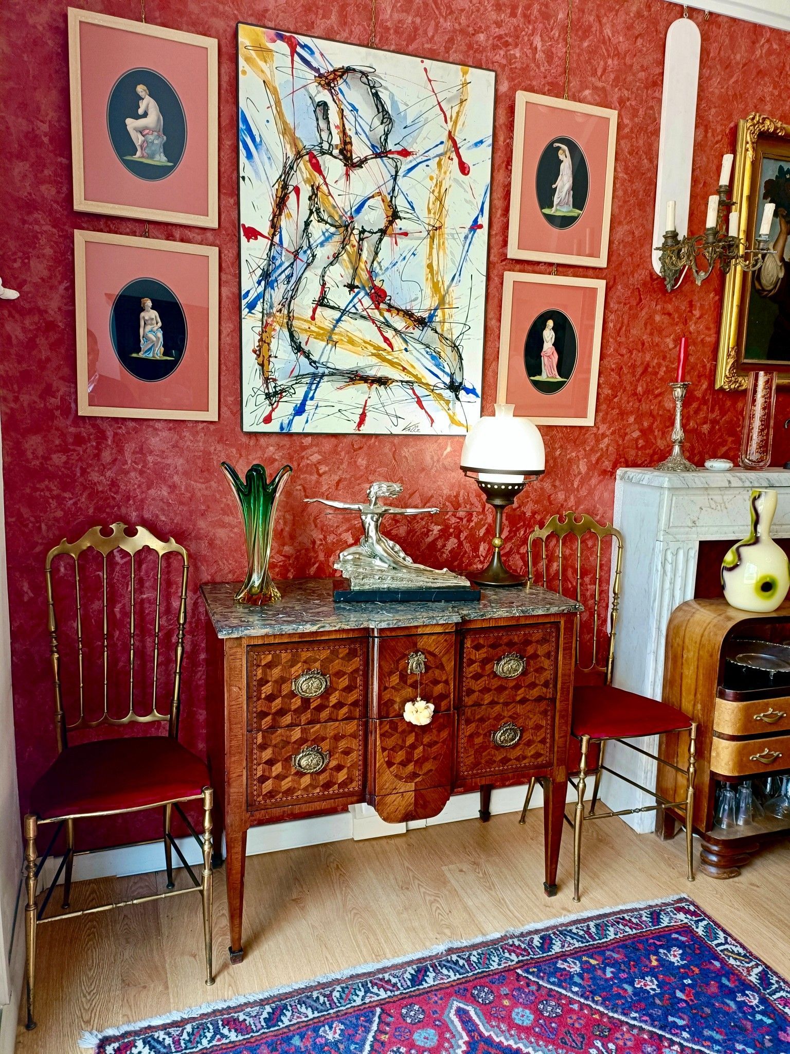 Un soggiorno con una cassettiera, sedie, un tappeto e un quadro alla parete.