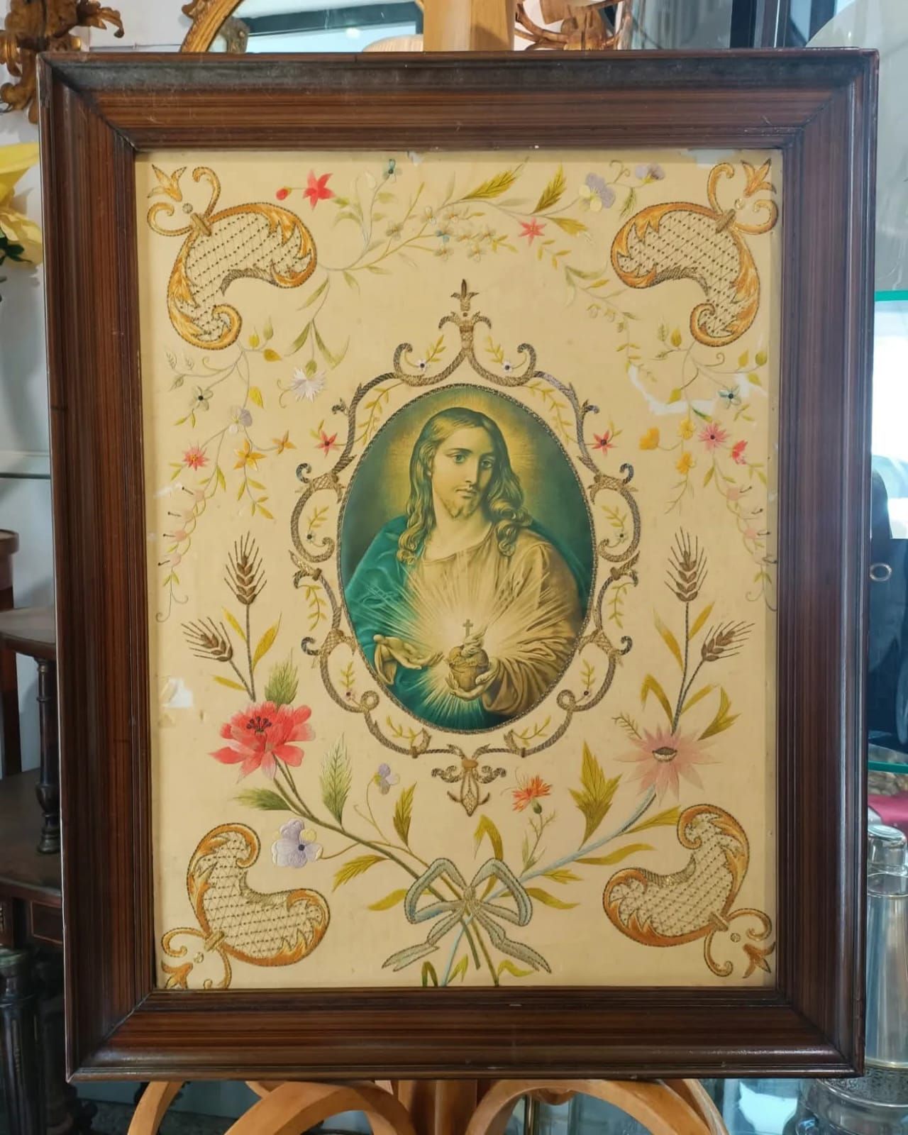 Un quadro incorniciato con fiori e una croce sopra