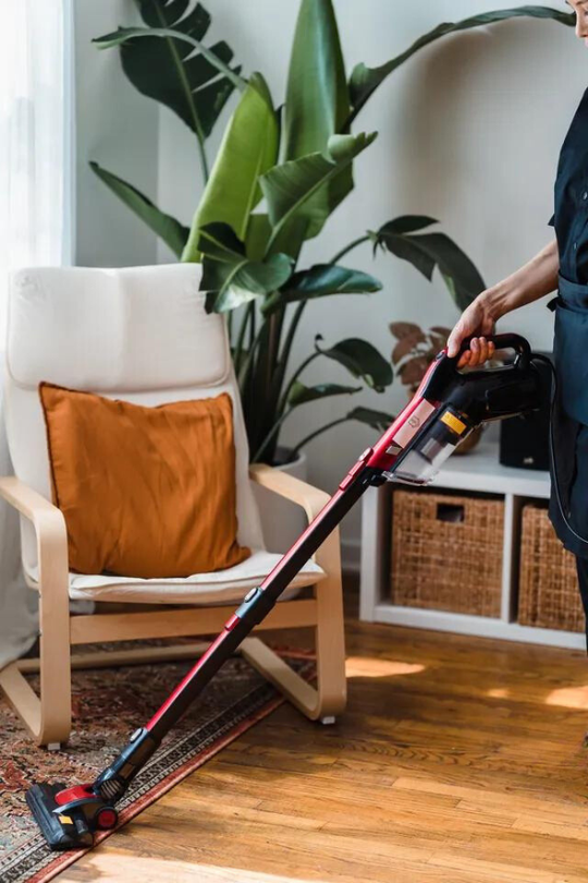 A person is using a vacuum cleaner to clean a rug in a living room.