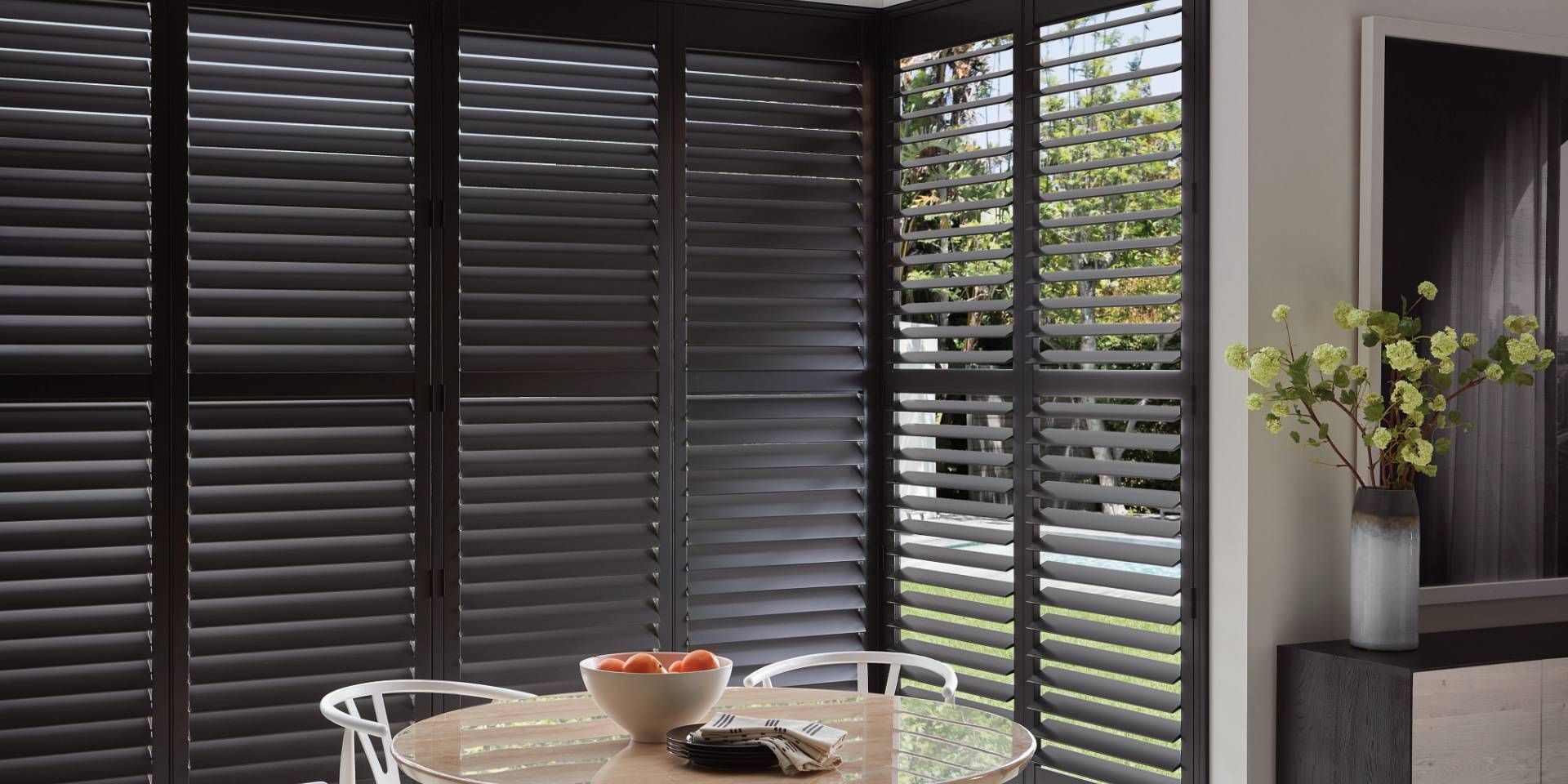 Hunter Douglas Heritance® Wood Shutters in a dark color on large windows in a kitchen
