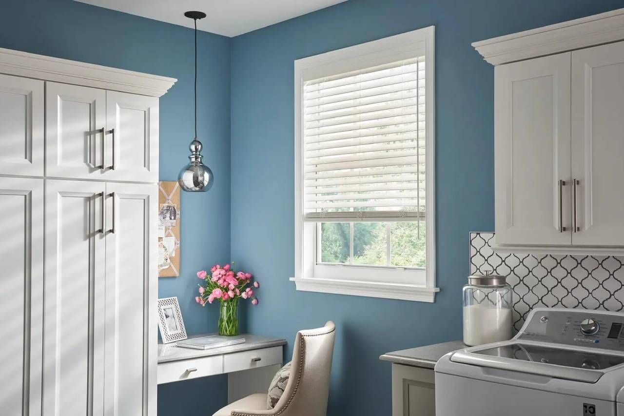 Alta Faux Wood Blinds on a window in a laundry room with blue walls