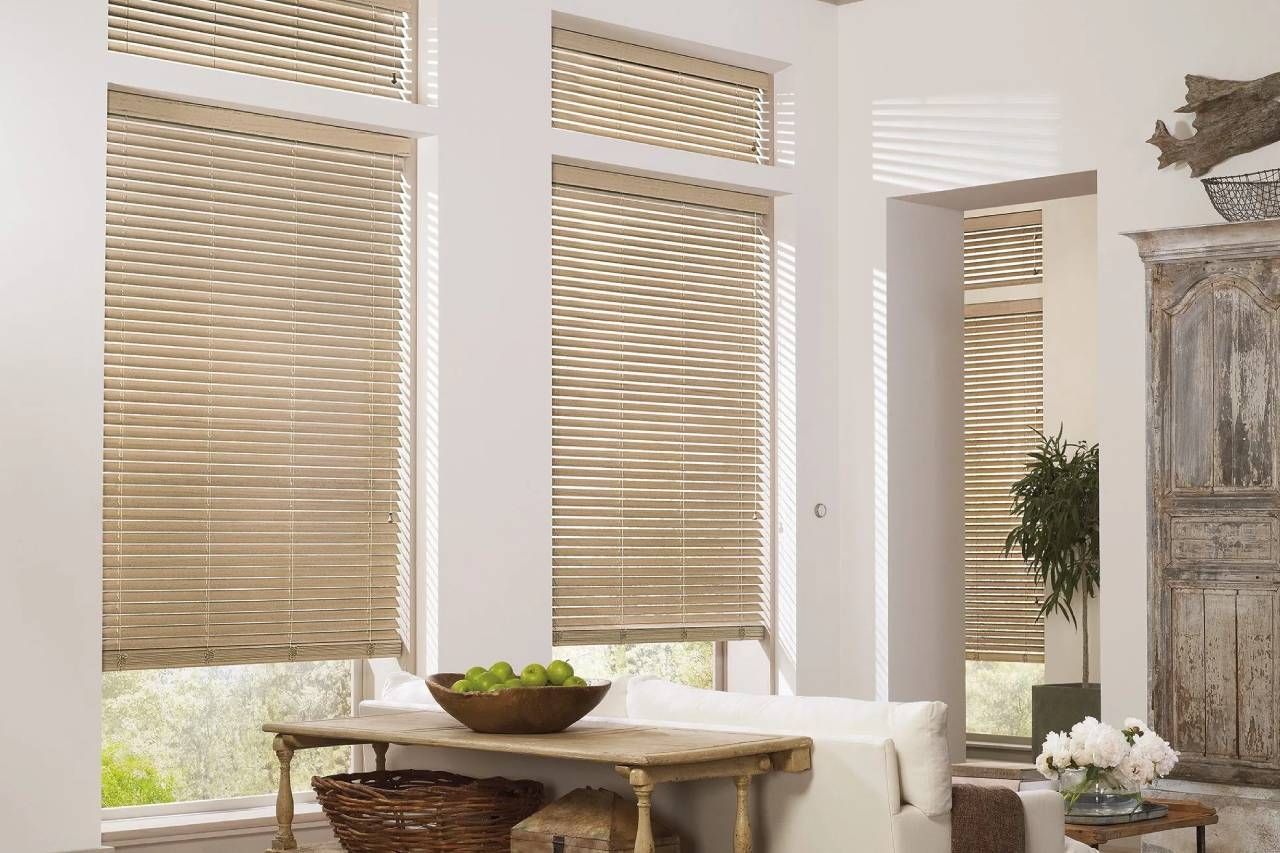 Chic and functional Hunter Douglas Parkland® Wood Blinds on several windows in a home’s living room