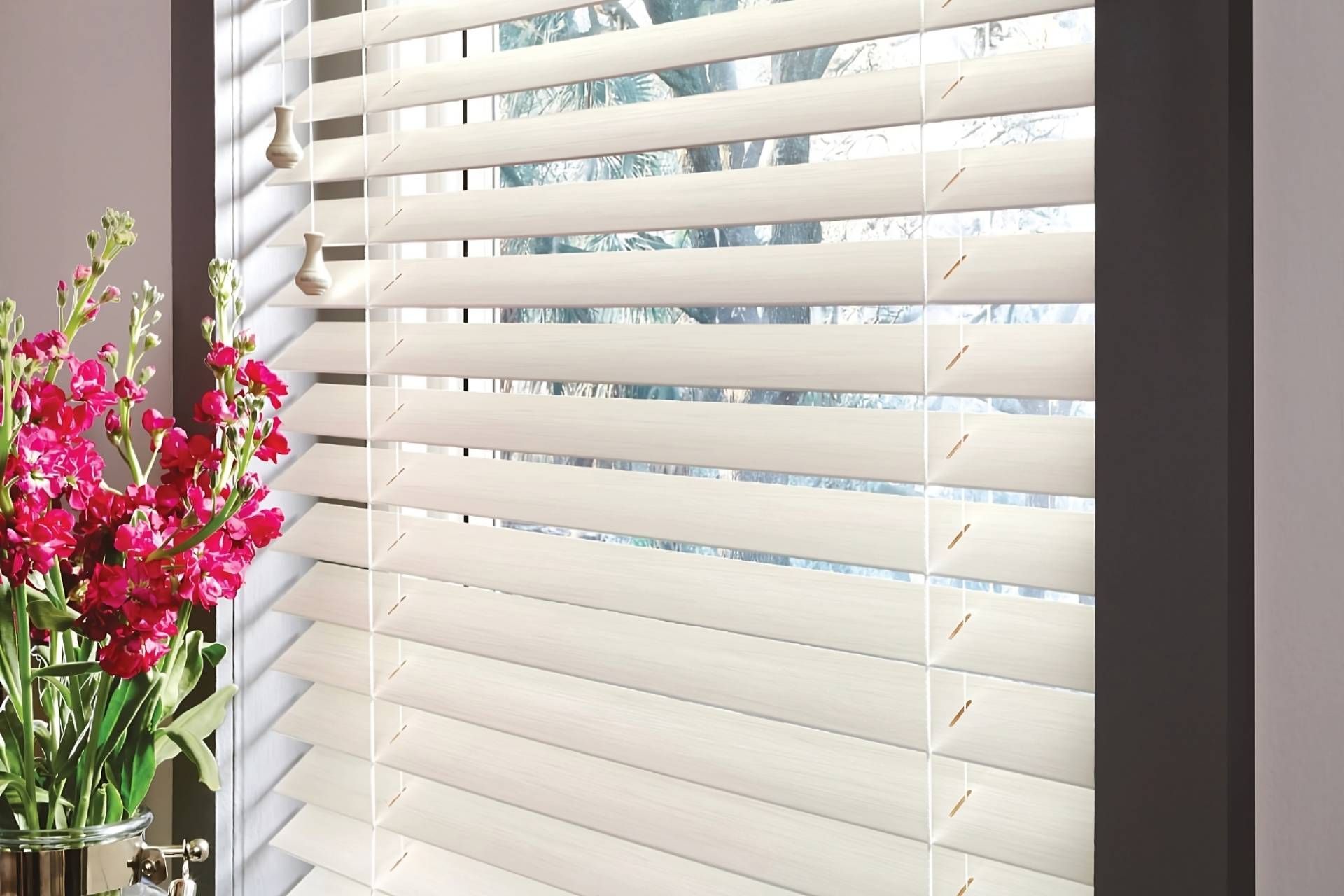 White Hunter Douglas Parkland® Wood Blinds, from Advantage Blinds, on a window near pink flowers nea