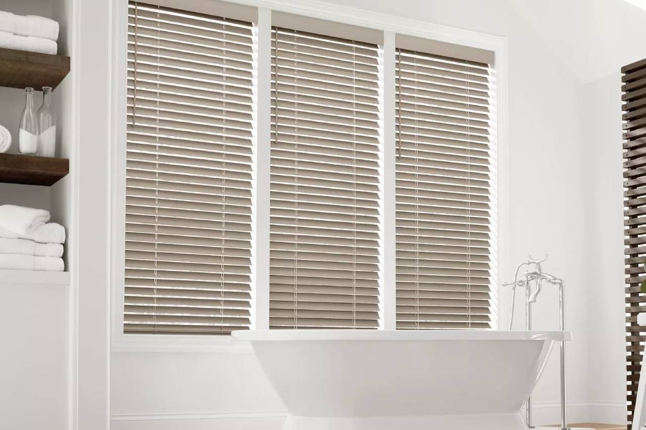 Stylish and durable Hunter Douglas EverWood® Faux Wood Blinds on bathroom windows near a tub