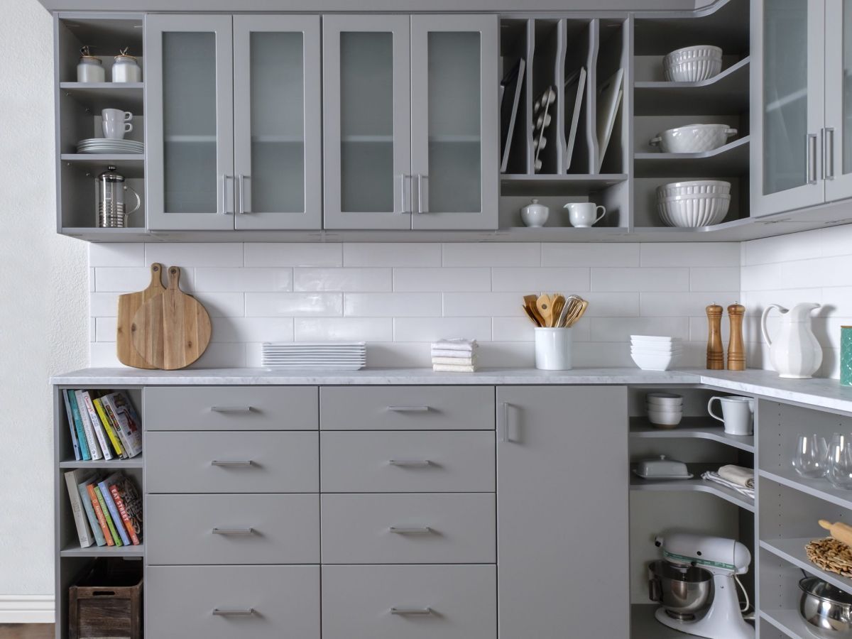 A kitchen with gray cabinets and white counter tops.