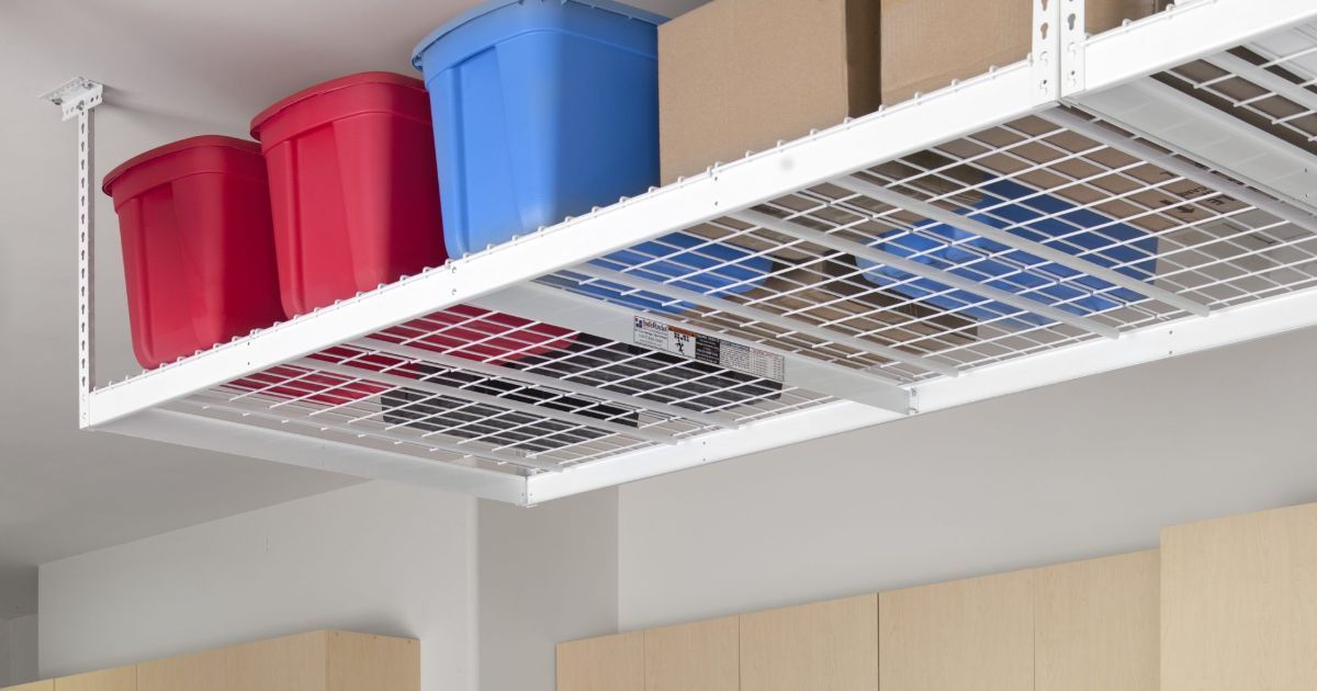 A overhead ceiling rack in a garage with boxes and bins on it.