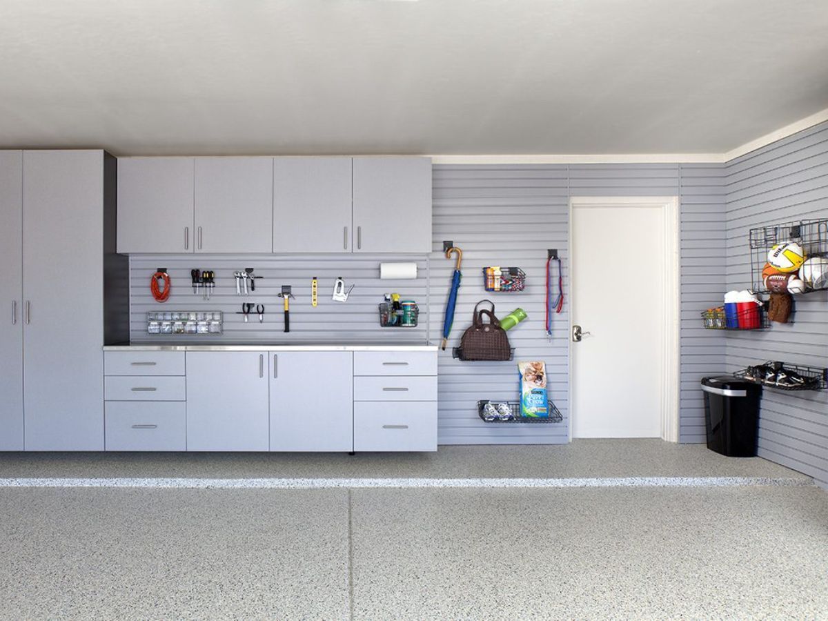 A garage cabinet and slatwall with accessories such as wire baskets, hooks and tool holders