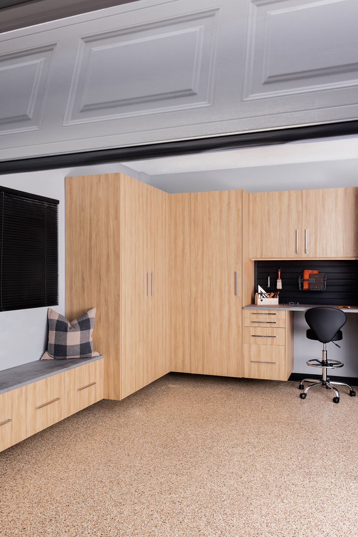 A garage with wooden cabinets , a desk and a chair.