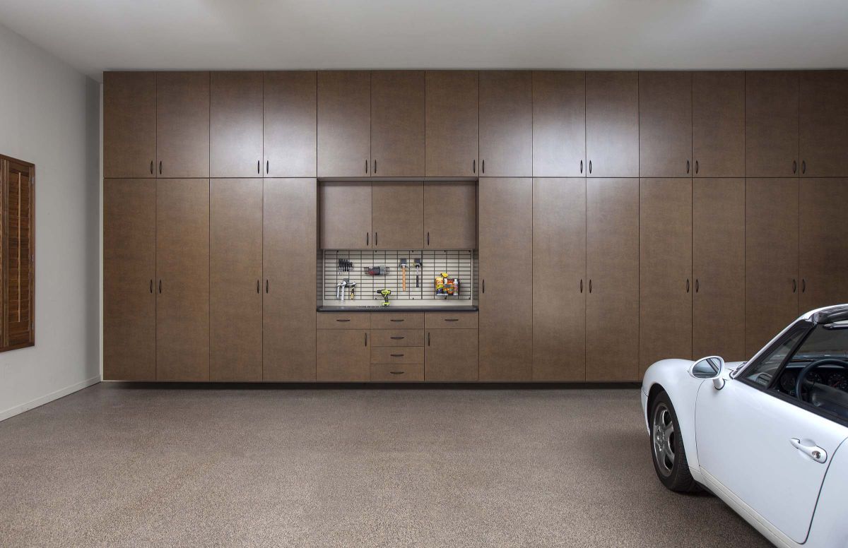 A white car is parked in a garage with lots of cabinets