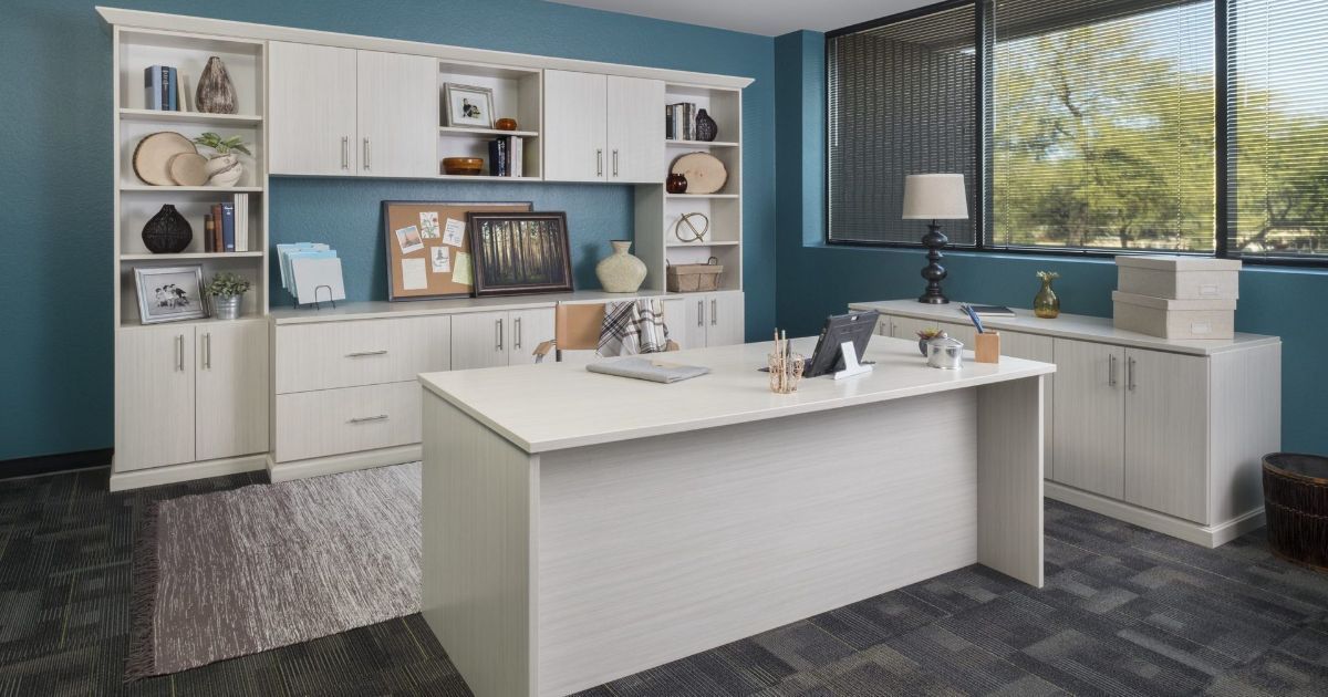 Modern bathroom with white cabinets, double sinks, blue walls, and a large island countertop near a window.