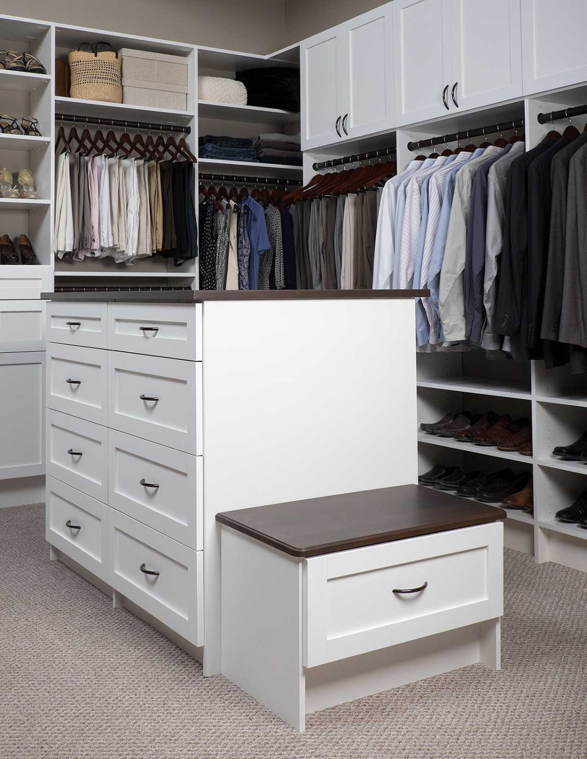 A walk in closet filled with lots of clothes and a bench.