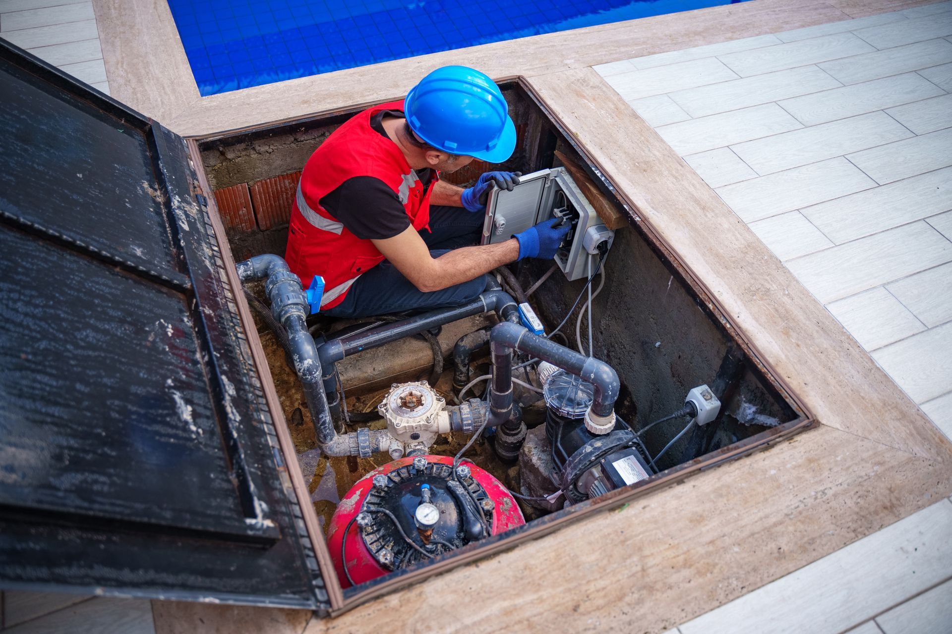 A man is working on a swimming pool pump.