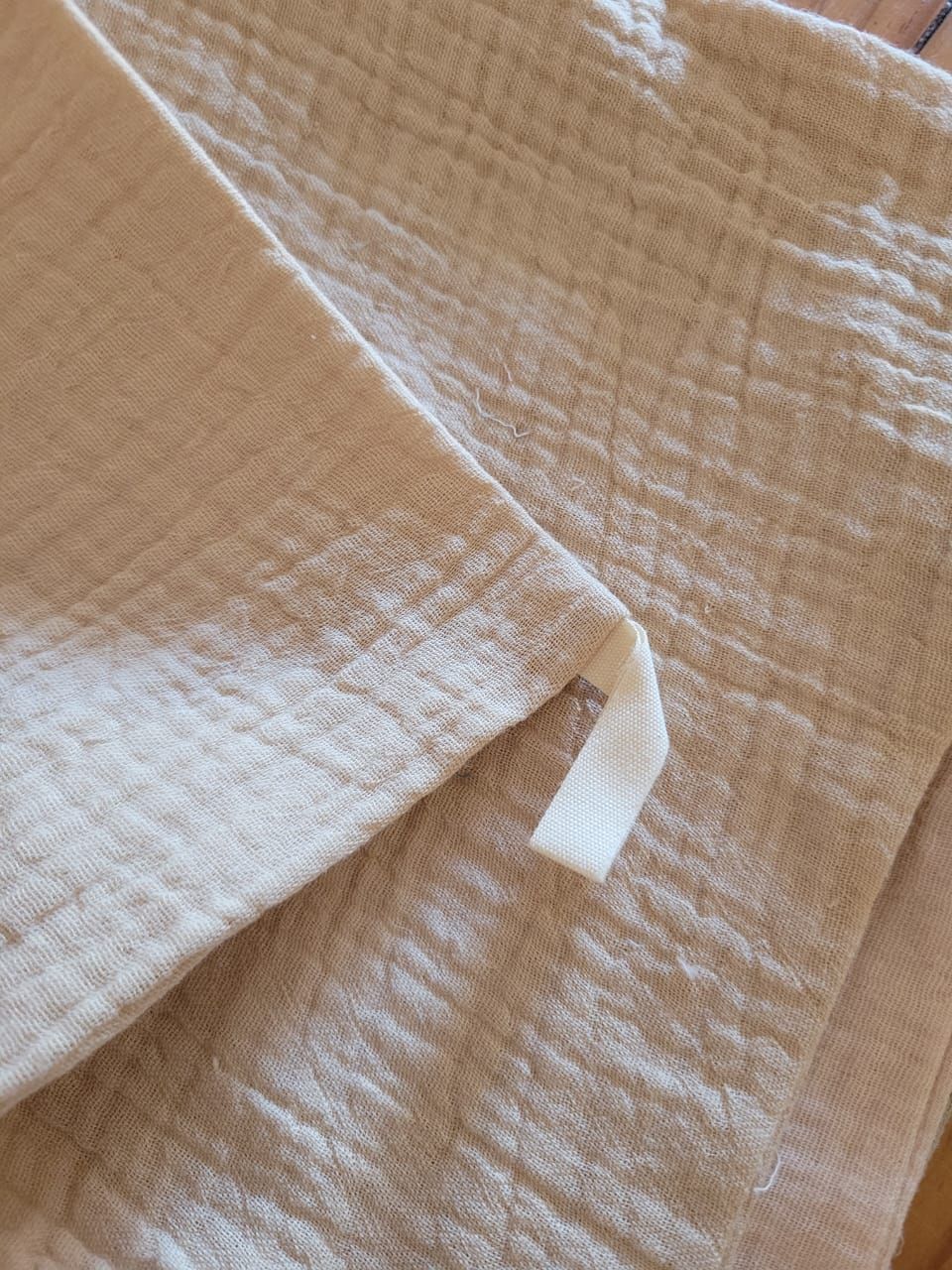 Primer plano de una manta tejida de color beige con una pequeña etiqueta de tela blanca.