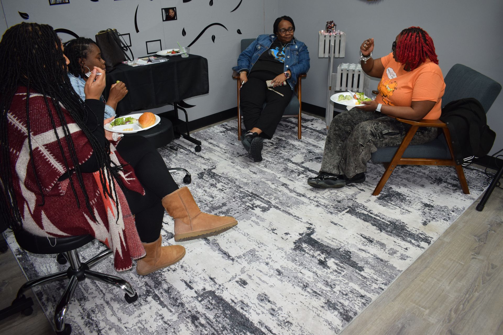 Small group seated in a living room, sharing drinks and snacks around a coffee table.