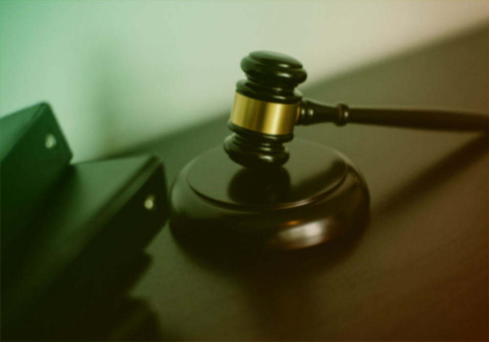 Judge’s gavel on a sound block beside a file folder, in warm greenish light