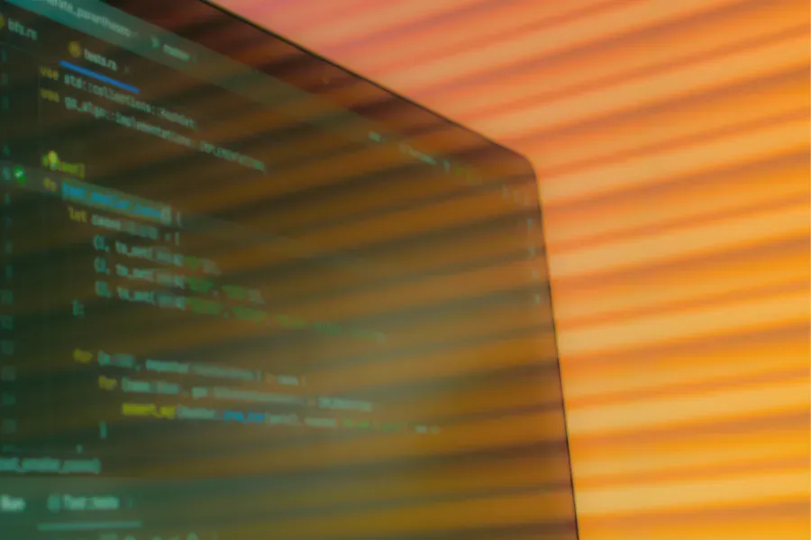 Close-up of a computer screen with colorful code on a warm orange background