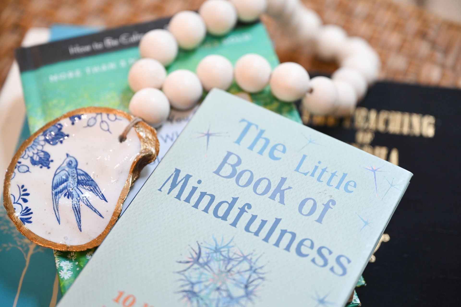 Books and a beaded accessory on a table, featuring The Little Book of Mindfulness cover