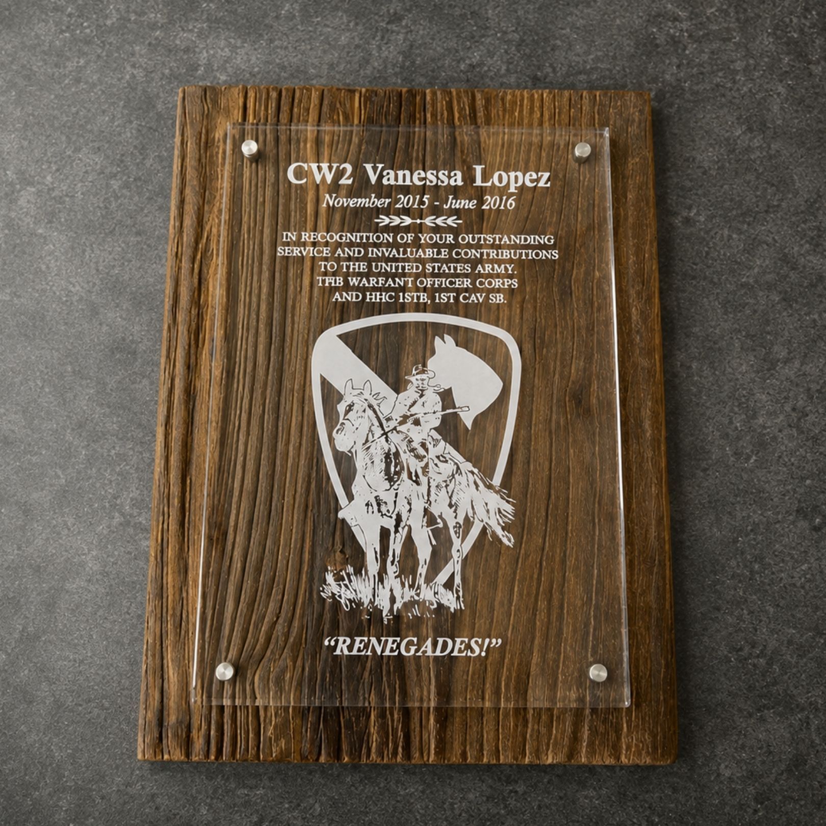 Wooden plaque with engraved text and a white Renegades logo on a gray surface