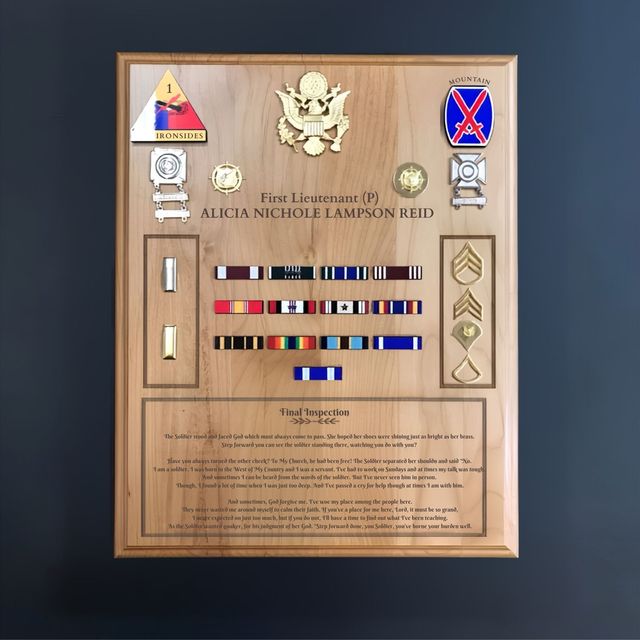 Framed military medal plaque with colorful ribbons, badges, and engraved text on a wood background