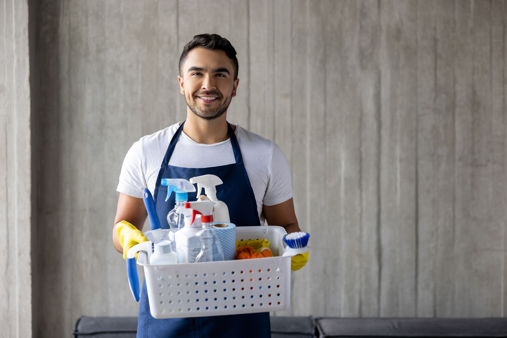 A man in an apron is holding a basket of cleaning supplies. A man in an apron is holding a basket of cleaning supplies.