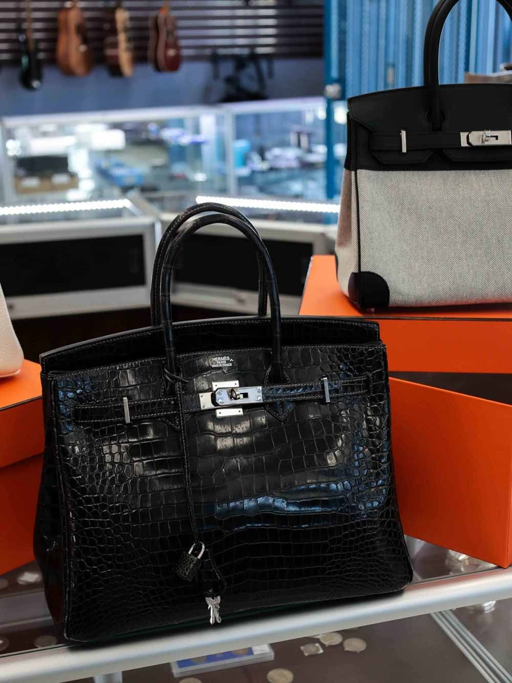 Black crocodile-texture handbag on an orange display shelf in a store