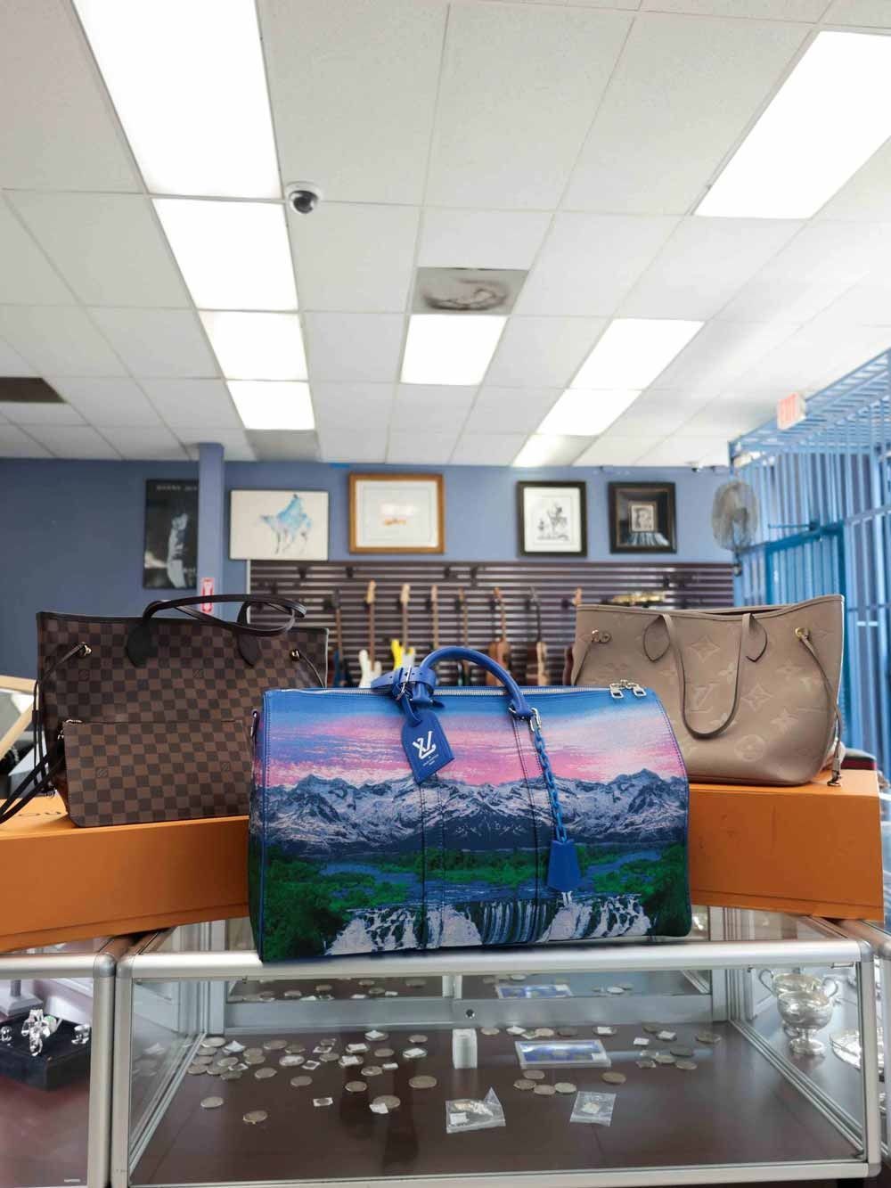 Retail display with two handbags, including a colorful scenic tote, on glass cases in a store